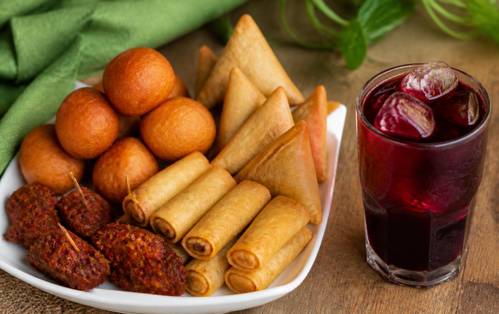 Platter of Nigerian small chops beside a glass of chilled zobo